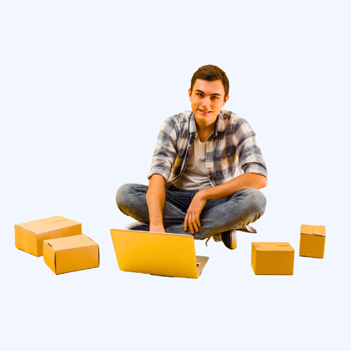 Surrounded by packages, a young man uses a laptop while seated on the floor.